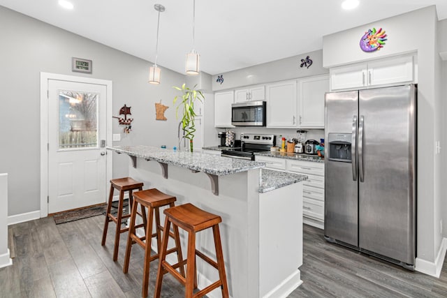 kitchen featuring hardwood / wood-style flooring, white cabinets, a kitchen island with sink, and appliances with stainless steel finishes