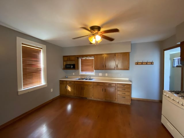 kitchen featuring white range with gas cooktop, sink, dark hardwood / wood-style floors, and ceiling fan