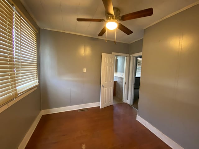 empty room with dark hardwood / wood-style flooring, ceiling fan, and crown molding