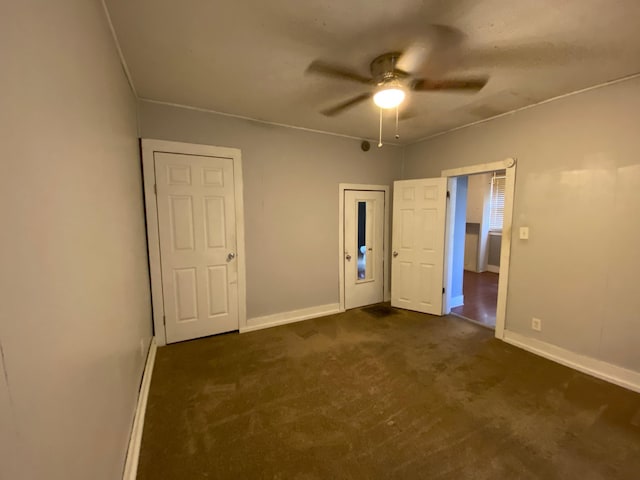 unfurnished bedroom with dark colored carpet and ceiling fan