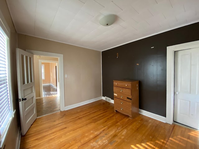 unfurnished bedroom featuring light wood-type flooring, crown molding, and a closet