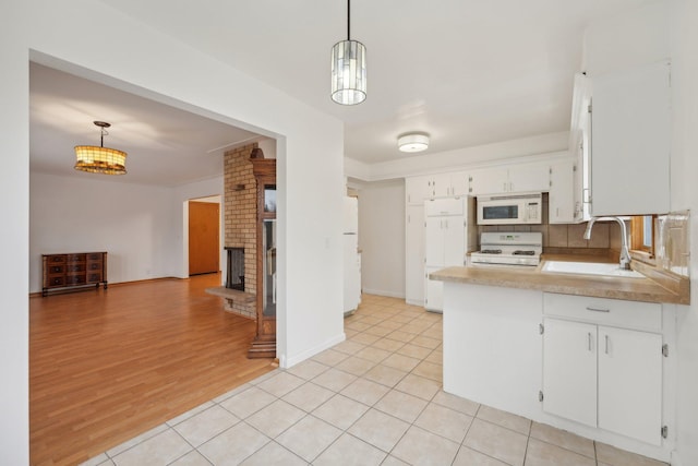 kitchen featuring sink, decorative light fixtures, white appliances, and light wood-type flooring