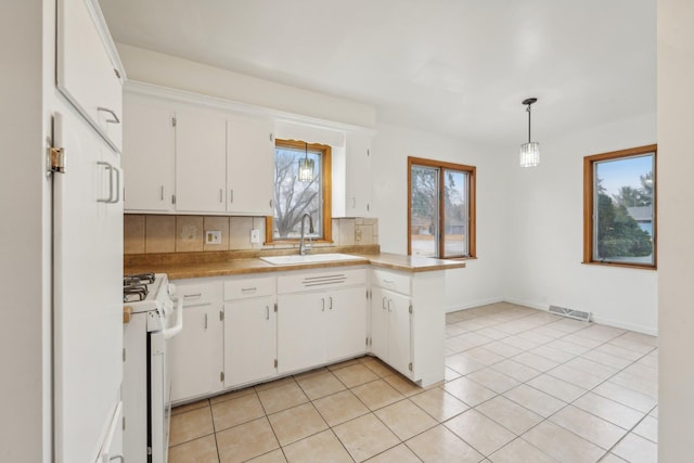 kitchen with white cabinetry, sink, hanging light fixtures, backsplash, and white range with gas cooktop