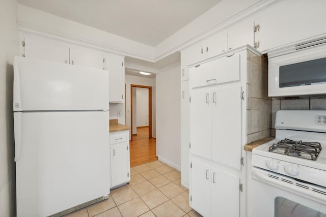 kitchen featuring white cabinets, light tile patterned flooring, and white appliances