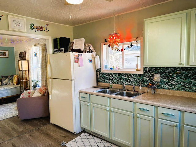 kitchen with dark hardwood / wood-style flooring, white refrigerator, decorative backsplash, a notable chandelier, and sink