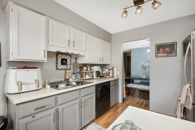 kitchen featuring black dishwasher, sink, white cabinetry, light hardwood / wood-style flooring, and stainless steel fridge