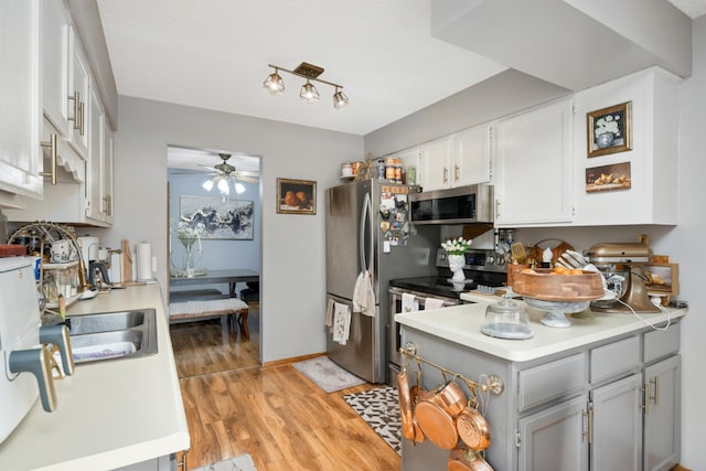 kitchen featuring stainless steel appliances, gray cabinets, sink, light hardwood / wood-style floors, and ceiling fan