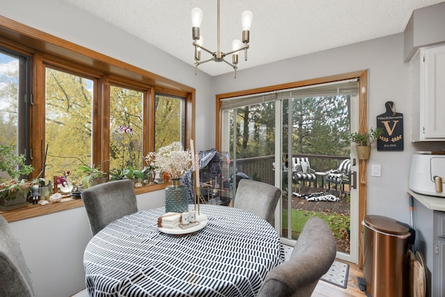 dining space with light wood-type flooring, a wealth of natural light, and a textured ceiling