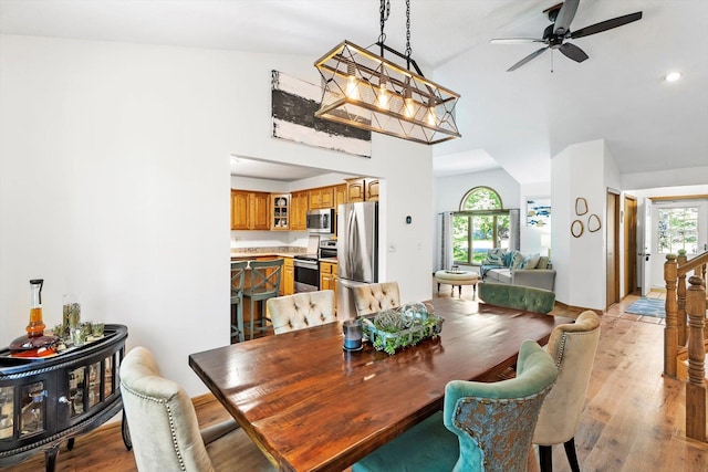 dining room with ceiling fan, lofted ceiling, and light wood-type flooring