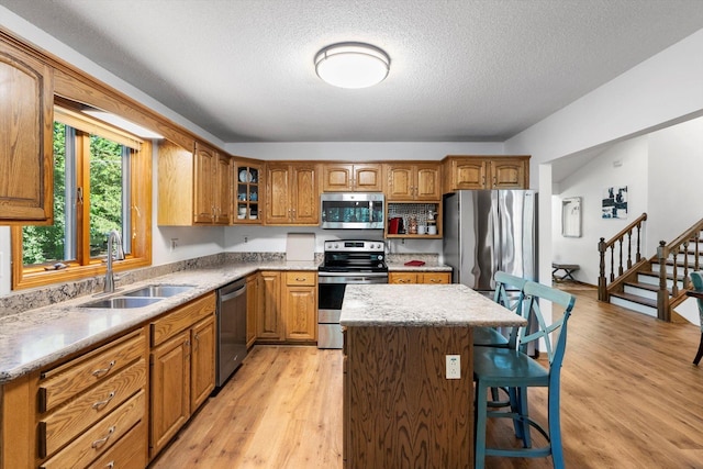 kitchen featuring a center island, sink, a textured ceiling, appliances with stainless steel finishes, and light hardwood / wood-style floors