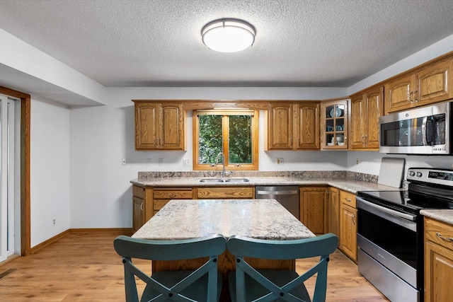 kitchen featuring a textured ceiling, light hardwood / wood-style floors, sink, and appliances with stainless steel finishes