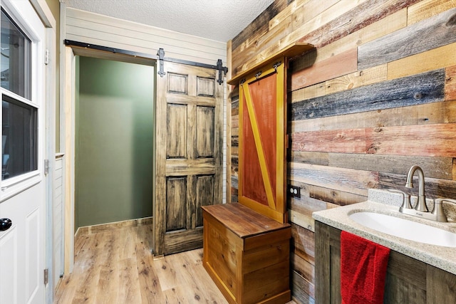 interior space with wood walls, vanity, a textured ceiling, and hardwood / wood-style flooring