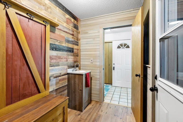 interior space with a textured ceiling, light wood-type flooring, and wood walls