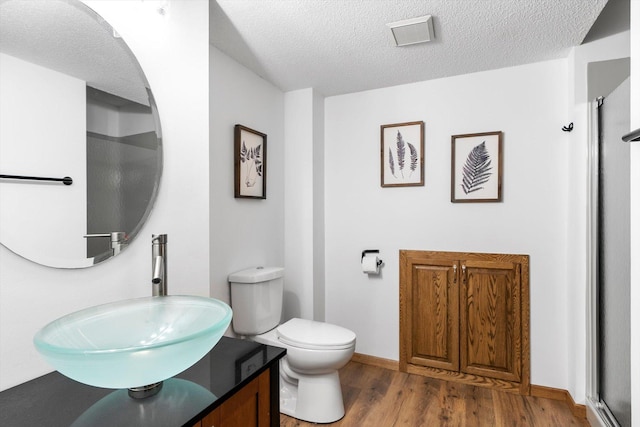 bathroom with hardwood / wood-style floors, vanity, a textured ceiling, and toilet