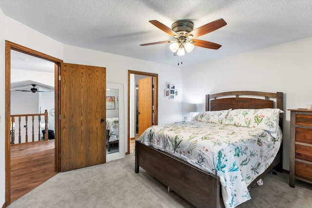 bedroom with ceiling fan, light wood-type flooring, a textured ceiling, and lofted ceiling