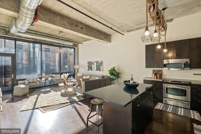 kitchen featuring dark brown cabinetry, a breakfast bar, wood-type flooring, a center island, and stainless steel appliances