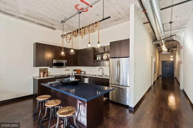 kitchen with a towering ceiling, stainless steel appliances, a center island, and sink