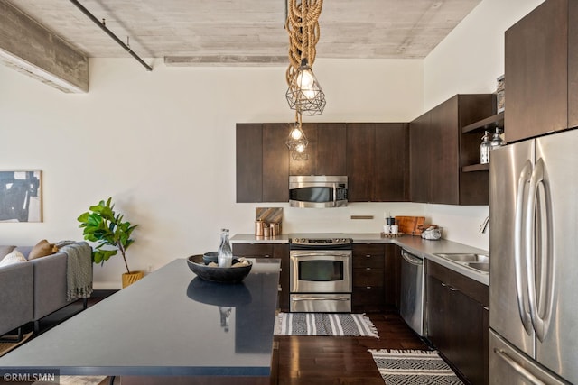 kitchen with stainless steel appliances, dark hardwood / wood-style floors, dark brown cabinetry, and decorative light fixtures