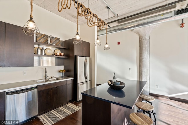 kitchen featuring sink, dark brown cabinets, a breakfast bar area, and appliances with stainless steel finishes