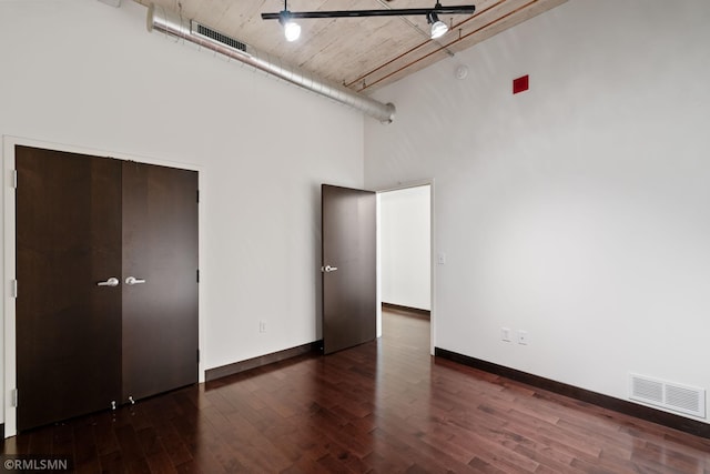 unfurnished bedroom featuring a high ceiling and dark hardwood / wood-style floors