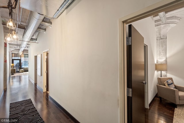 hall with a towering ceiling and dark hardwood / wood-style floors