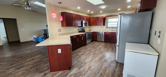 kitchen with pendant lighting, dark wood-type flooring, sink, appliances with stainless steel finishes, and kitchen peninsula