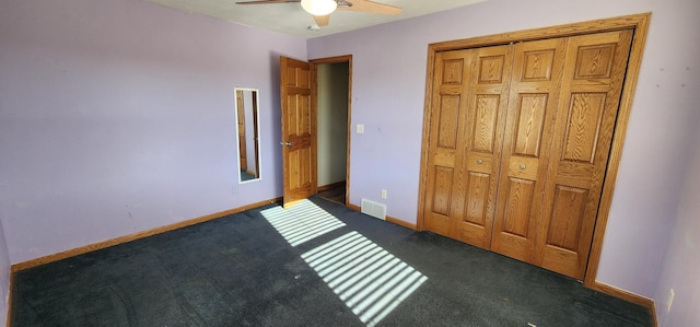 unfurnished bedroom featuring dark colored carpet, a closet, and ceiling fan