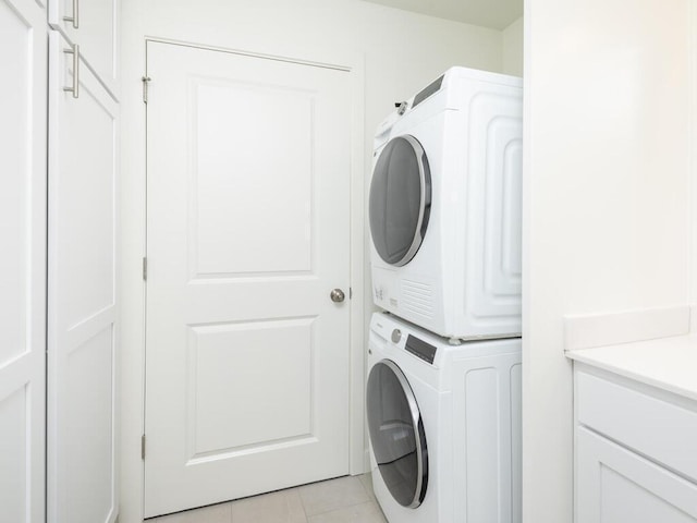 clothes washing area with light tile patterned flooring and stacked washing maching and dryer