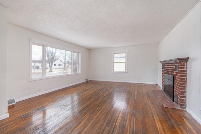 unfurnished living room with dark wood-type flooring, a brick fireplace, and a textured ceiling