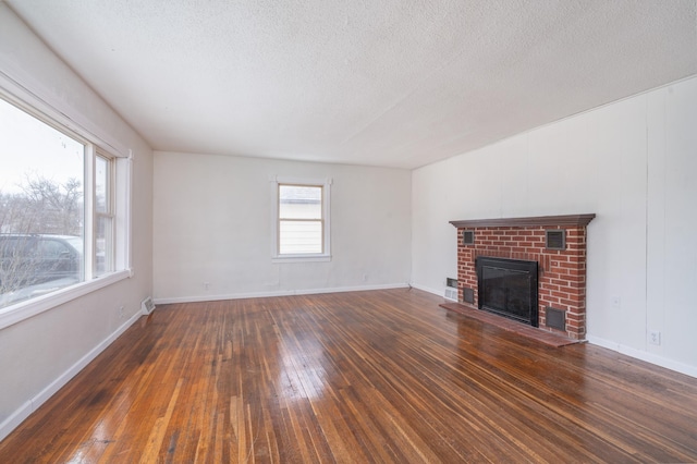 unfurnished living room featuring dark wood-type flooring, a textured ceiling, and a fireplace