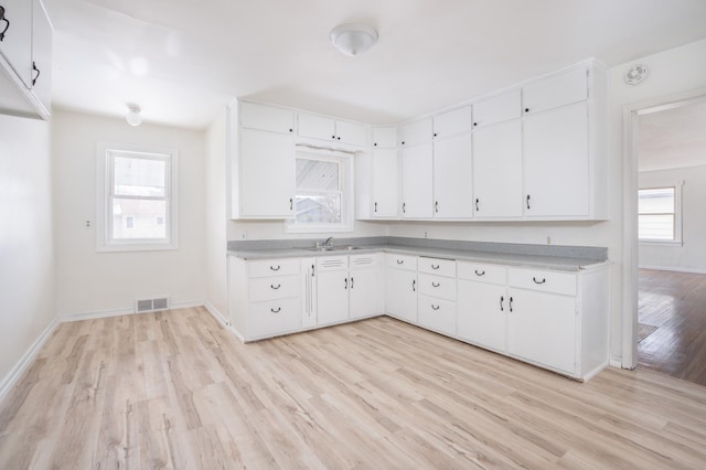 kitchen with sink, light wood-type flooring, and white cabinets