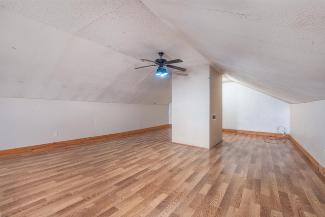 additional living space featuring ceiling fan, vaulted ceiling, light hardwood / wood-style floors, and a textured ceiling