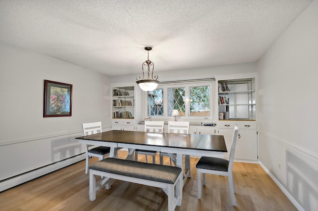 dining room with a textured ceiling, light wood-type flooring, and baseboard heating