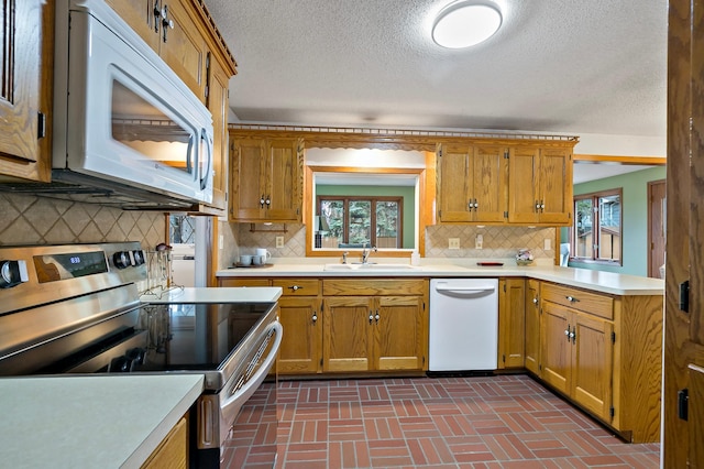 kitchen with a textured ceiling, white appliances, tasteful backsplash, and sink