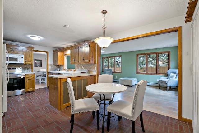 dining room featuring sink, baseboard heating, and a textured ceiling