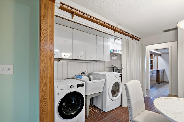 clothes washing area featuring cabinets and washing machine and dryer