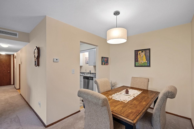 dining area with a textured ceiling and light carpet