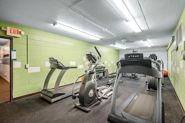 workout area with ceiling fan and a textured ceiling