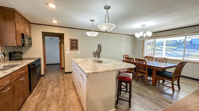 kitchen with light hardwood / wood-style flooring, backsplash, black / electric stove, pendant lighting, and a kitchen island