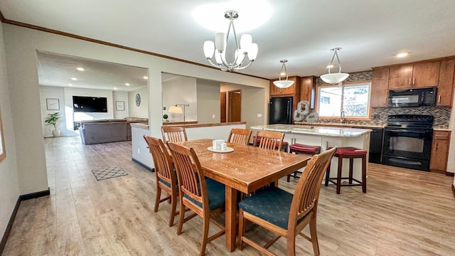 dining area with light hardwood / wood-style flooring, a notable chandelier, crown molding, and sink