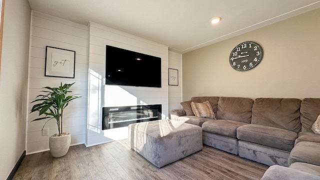 living room featuring hardwood / wood-style floors, a large fireplace, and ornamental molding