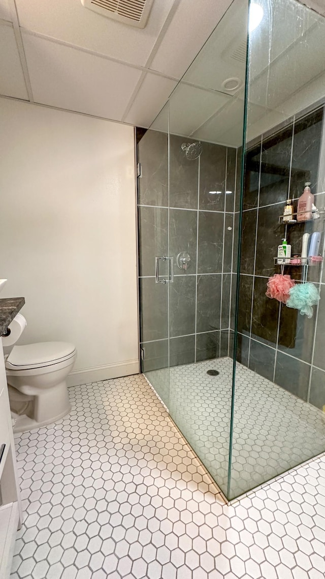 bathroom featuring tile patterned flooring, a shower with shower door, and toilet