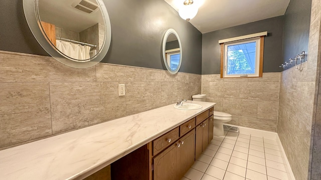 bathroom featuring tile patterned flooring, vanity, tile walls, and toilet