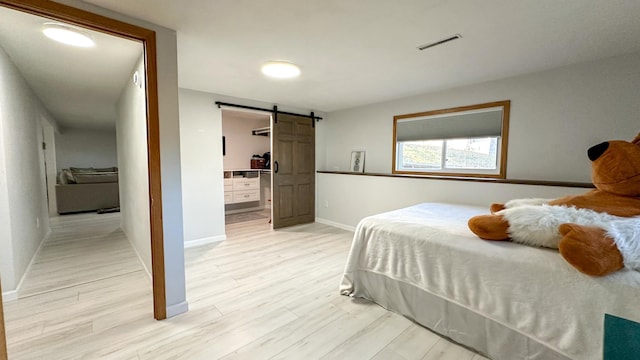 bedroom featuring light wood-type flooring and a barn door