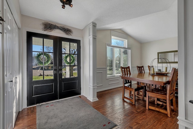 foyer with dark wood-type flooring, vaulted ceiling, a textured ceiling, and french doors