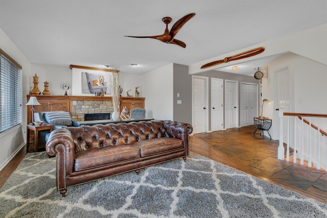 living room with dark wood-type flooring, ceiling fan, and a fireplace