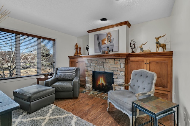 living area with a textured ceiling, hardwood / wood-style floors, and a fireplace