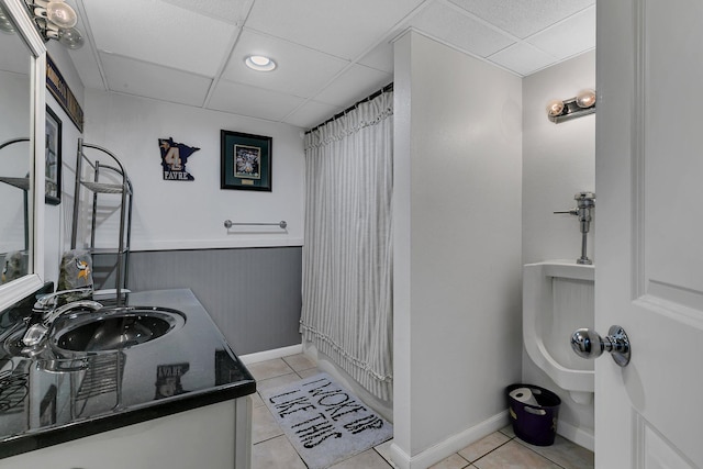 bathroom with a paneled ceiling, tile patterned floors, and vanity