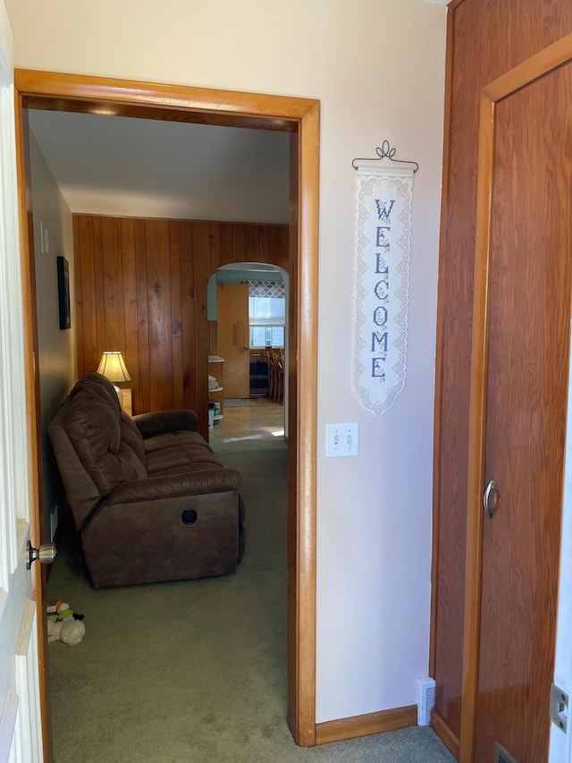 hall with wood walls and carpet floors