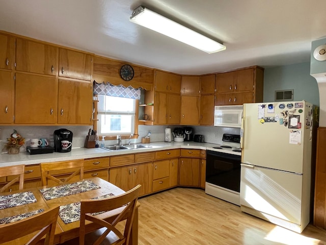 kitchen with decorative backsplash, white appliances, light hardwood / wood-style flooring, and sink